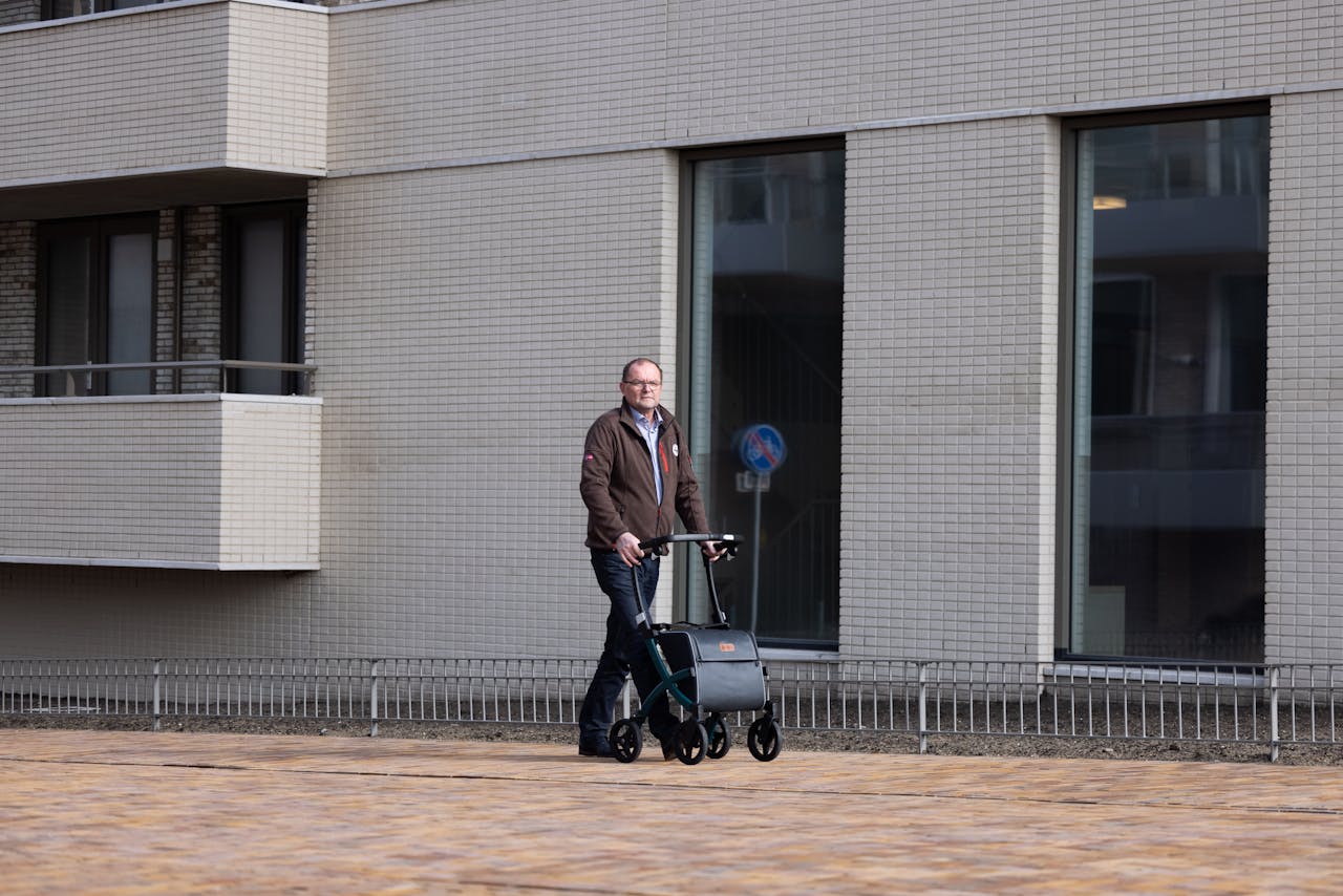 our-story Elderly man using rollator for support while strolling along a city street, showcasing urban mobility.